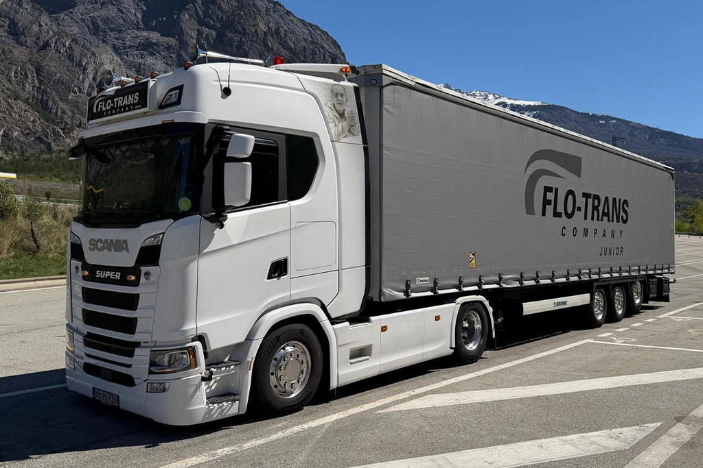 Un ansamblu cap tractor si semi-remorca cu prelata inscriptionate cu logo-ul oficial al companiei Flo-Trans Company Junior