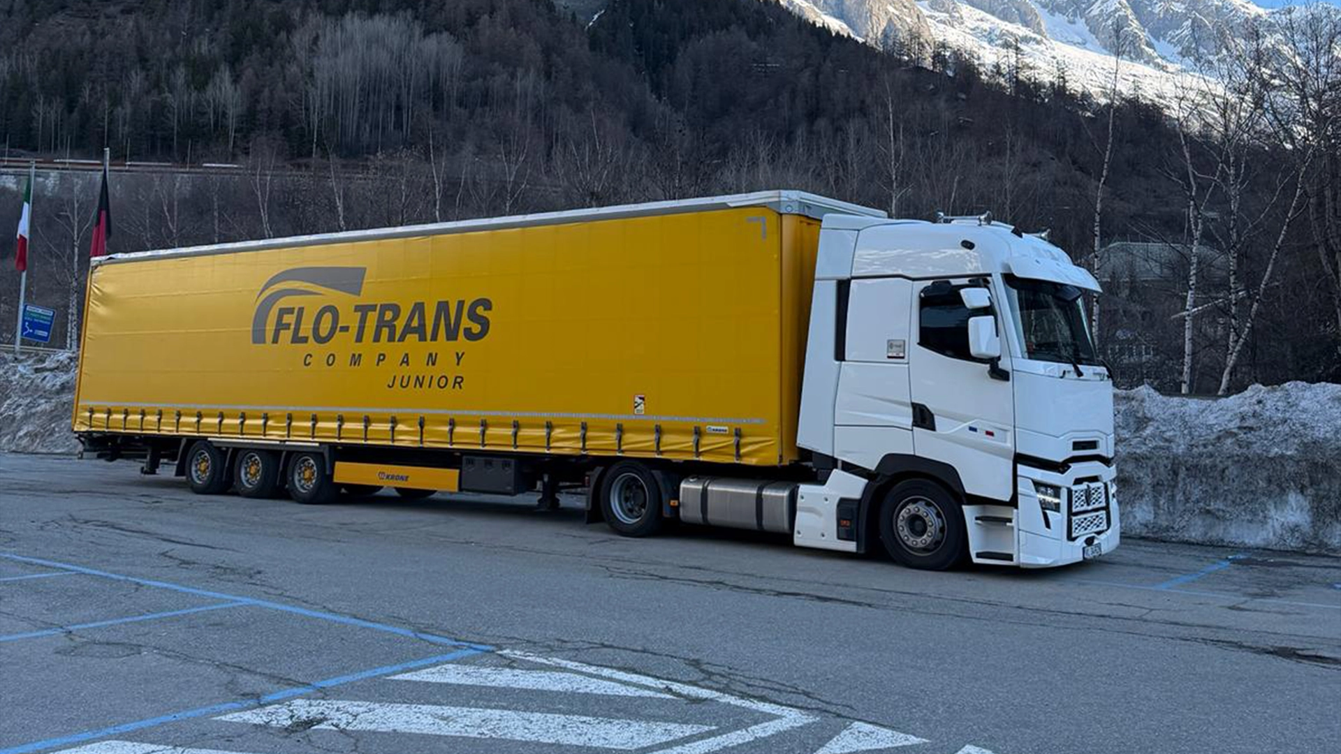 Cap tractor Renault de ultima generatie ce tracteaza o semi-remorca cu prelata inscriptionata cu logo-ul companiei