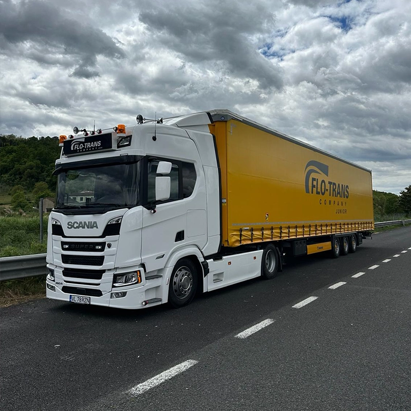 Camion Scania tractand o semi-remorca cu prelata galben inchis inscriptionata cu logo-ul companiei